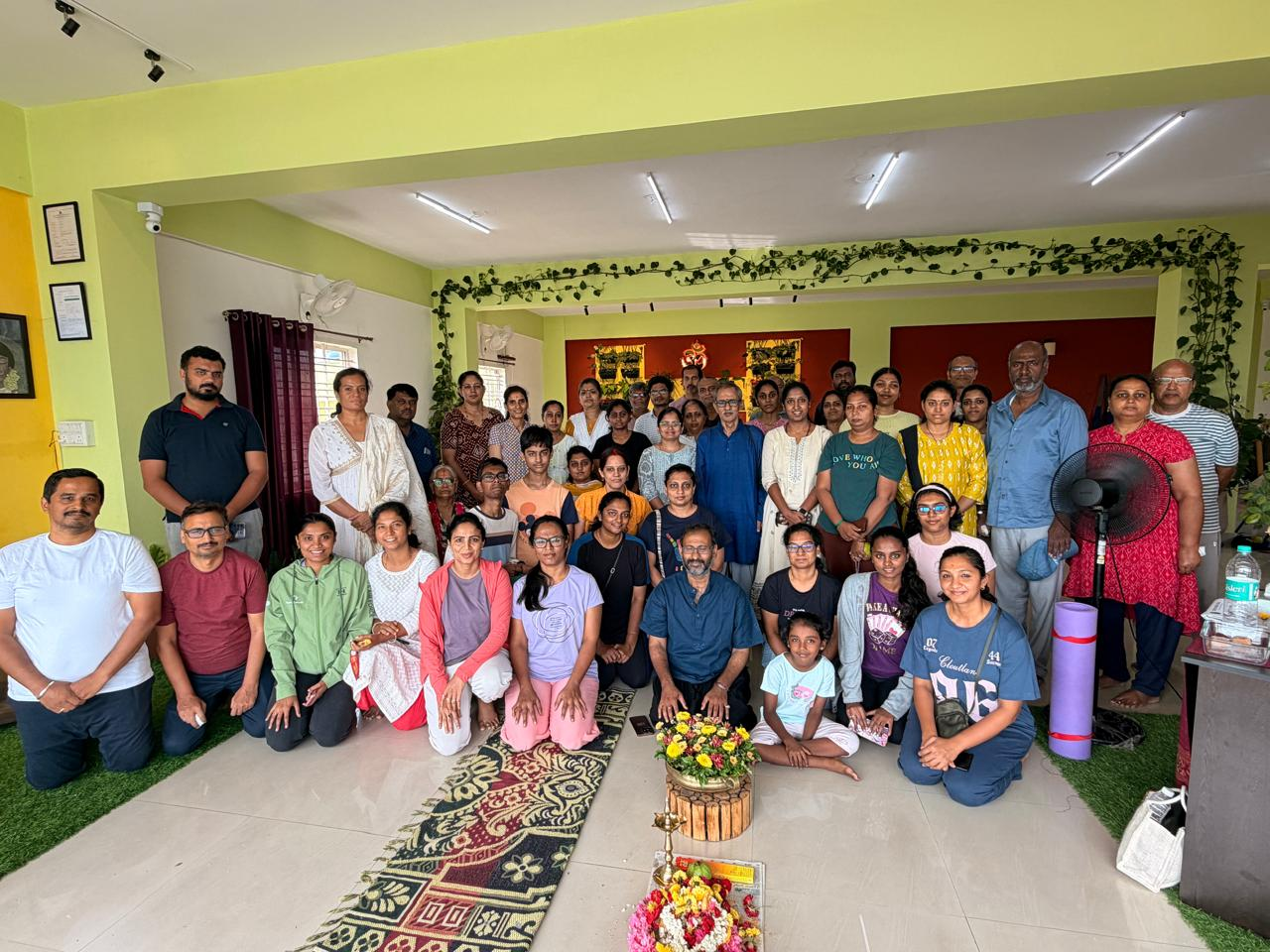 A large group of students gathered in the studio with flowers and offerings