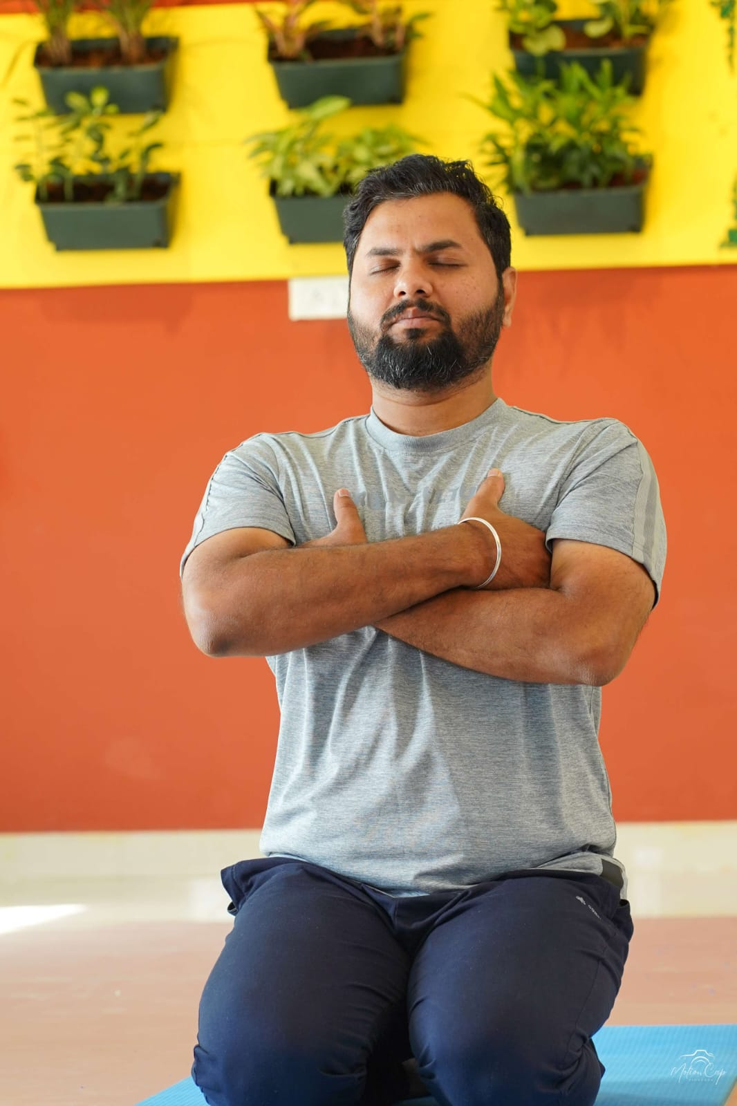 A practitioner kneeling with hands crossed over the heart in quiet reflection