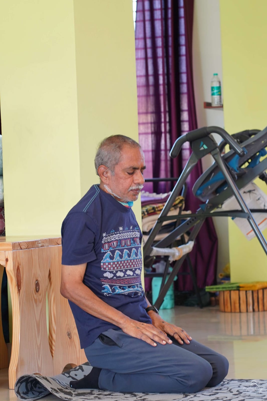 An older student seated in quiet meditation inside the studio