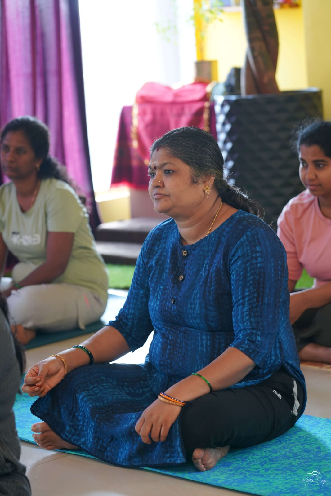 A student seated in steady meditation during a group class