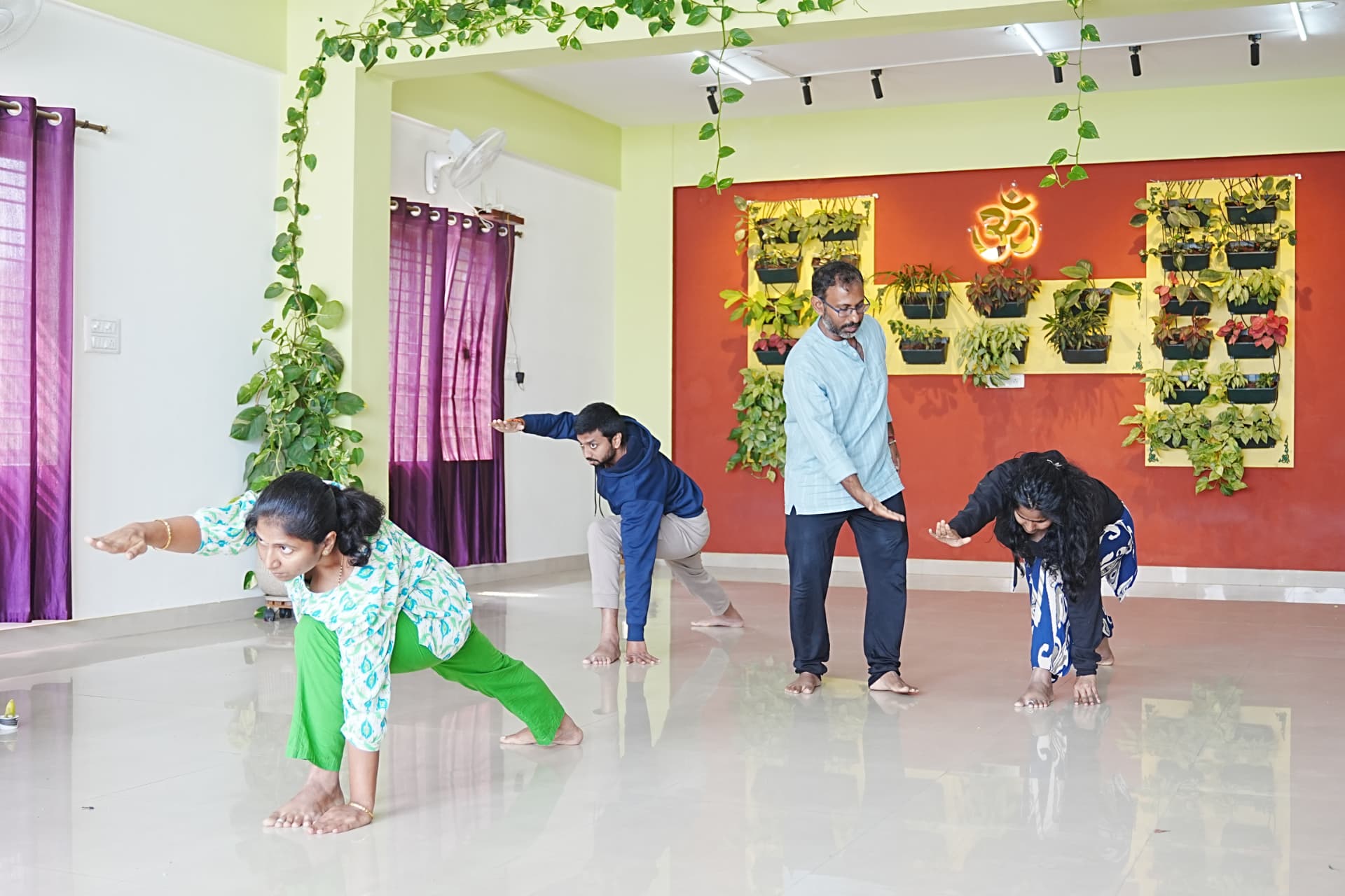 A teacher guiding three students through a standing yoga sequence