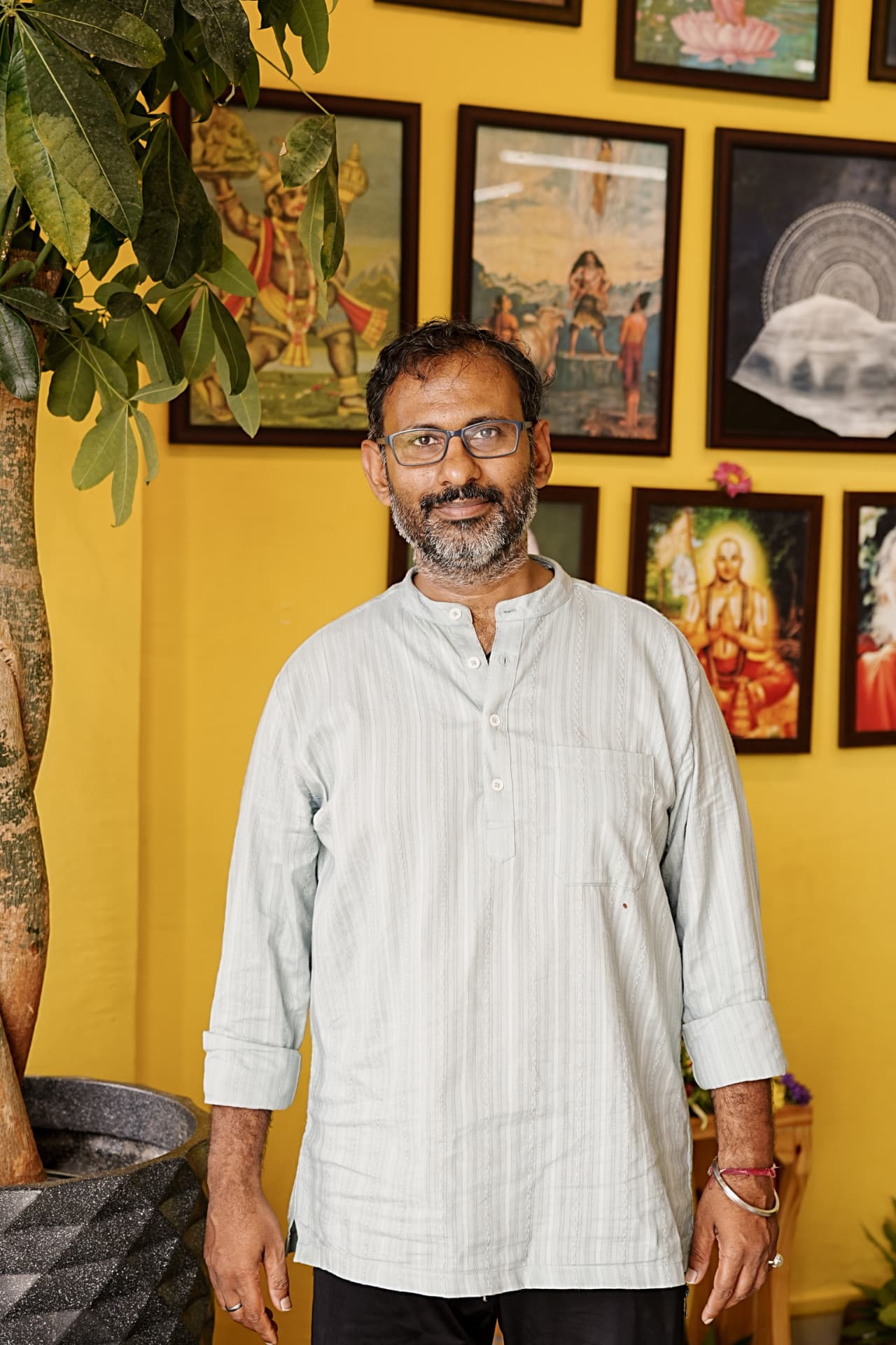 The teacher of Guru Paduka Yoga standing before the studio's picture wall