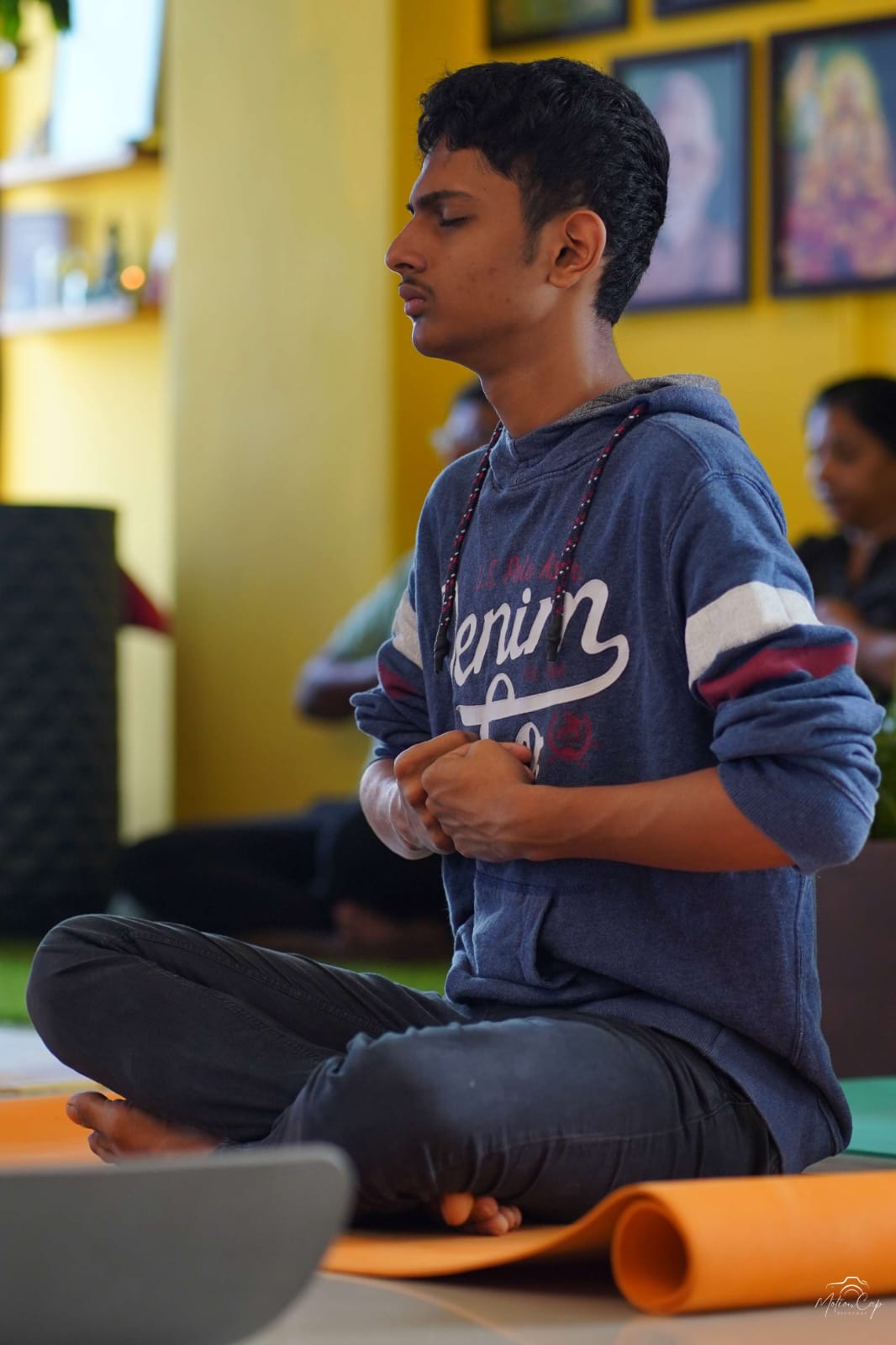 A student seated in meditation holding a mudra during practice