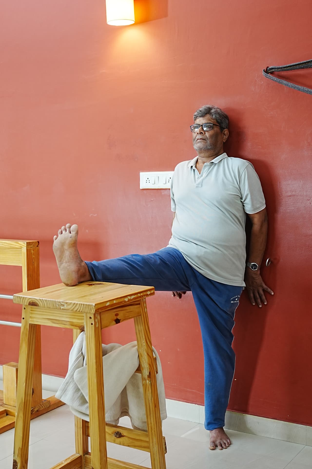 A student practising a supported standing pose using a wooden stool