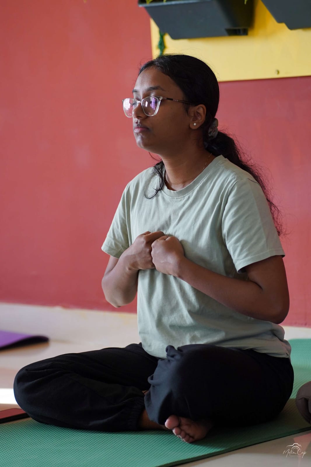 A seated practitioner with hands resting at the chest in quiet practice