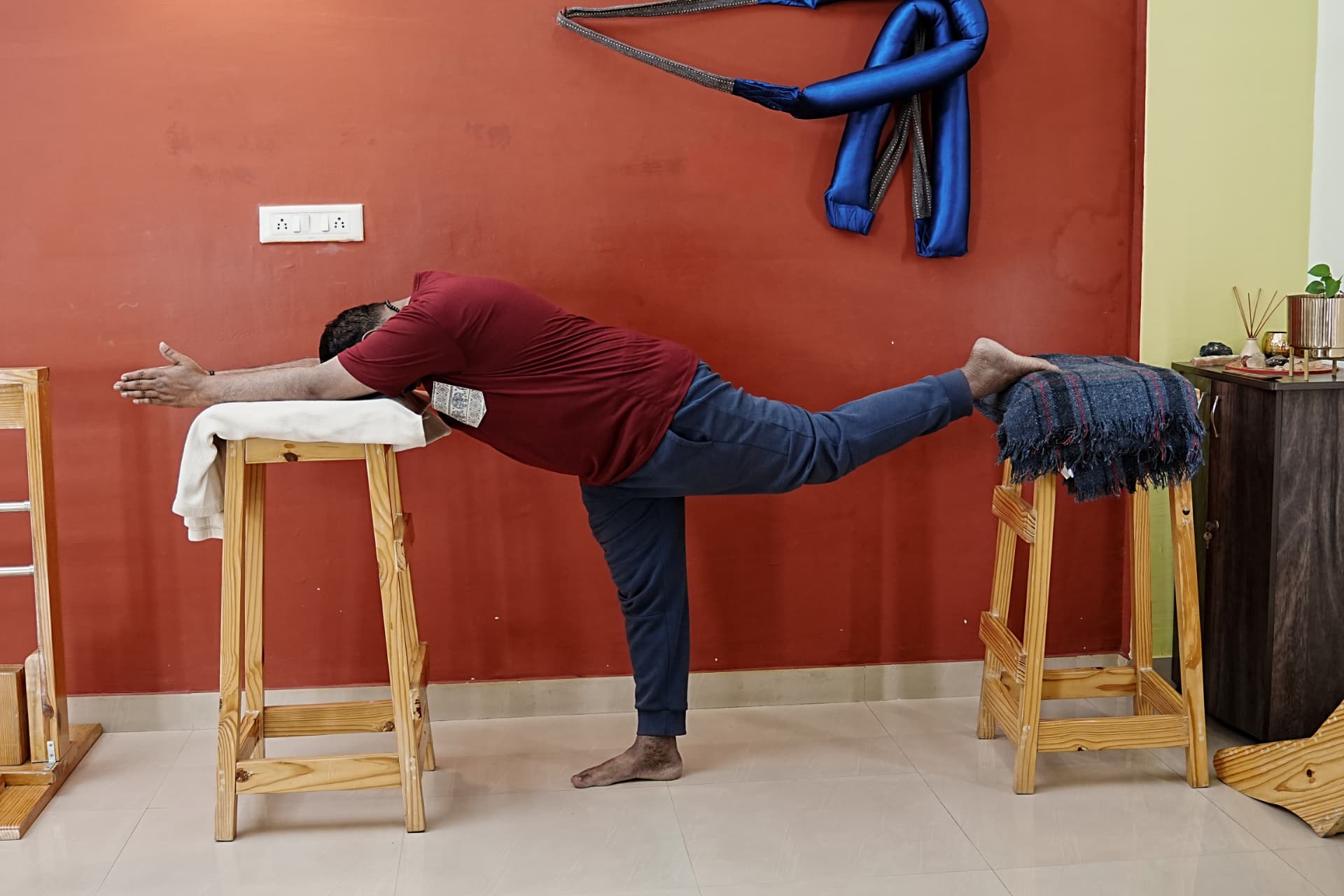 A practitioner supported on two wooden stools in a forward extension