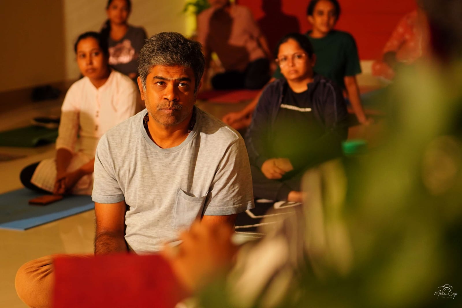 Students seated in stillness during an evening session in the practice hall