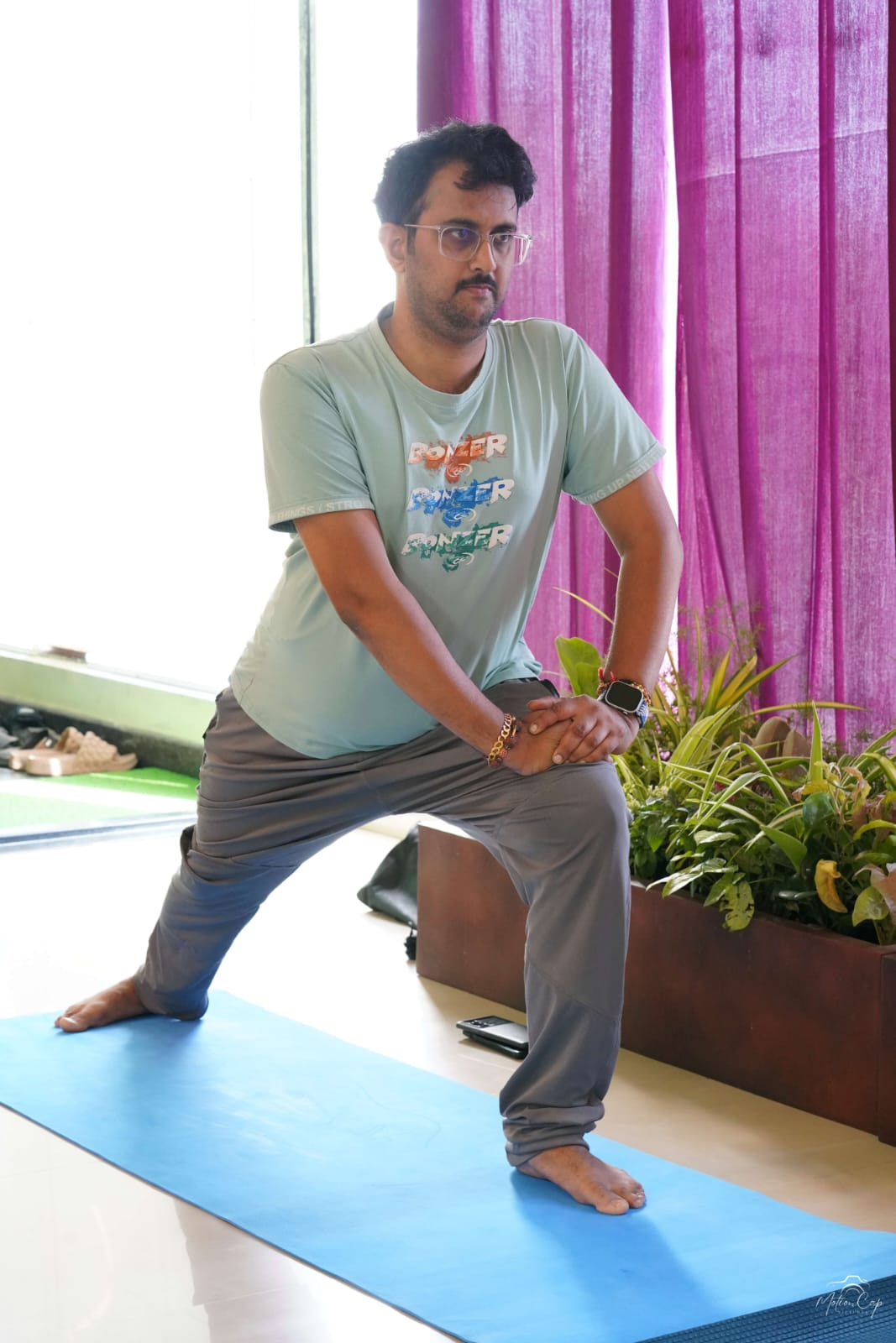 A practitioner in a wide-legged standing pose on a blue yoga mat
