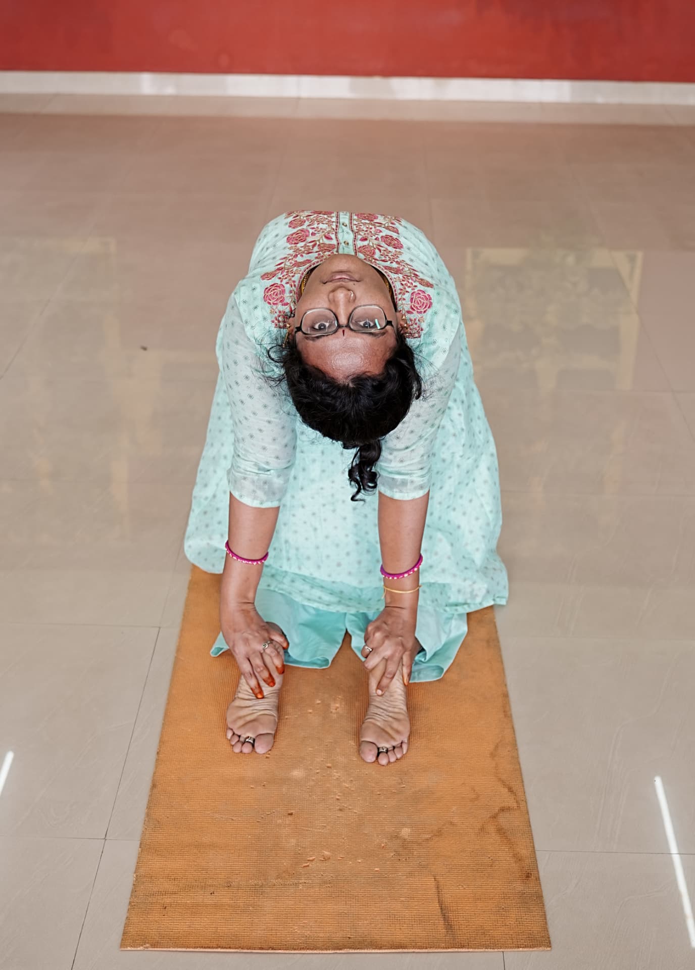 A student in a seated forward bend on a jute mat