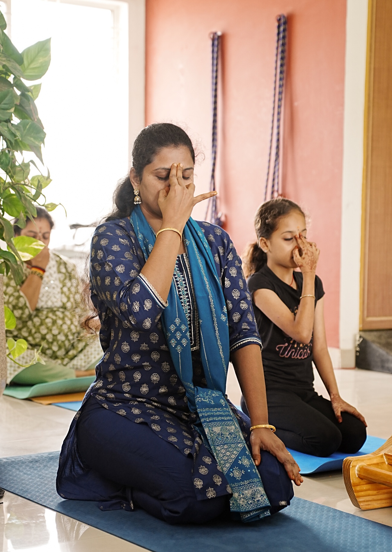 Students seated in pranayama practice with hands in nasika mudra