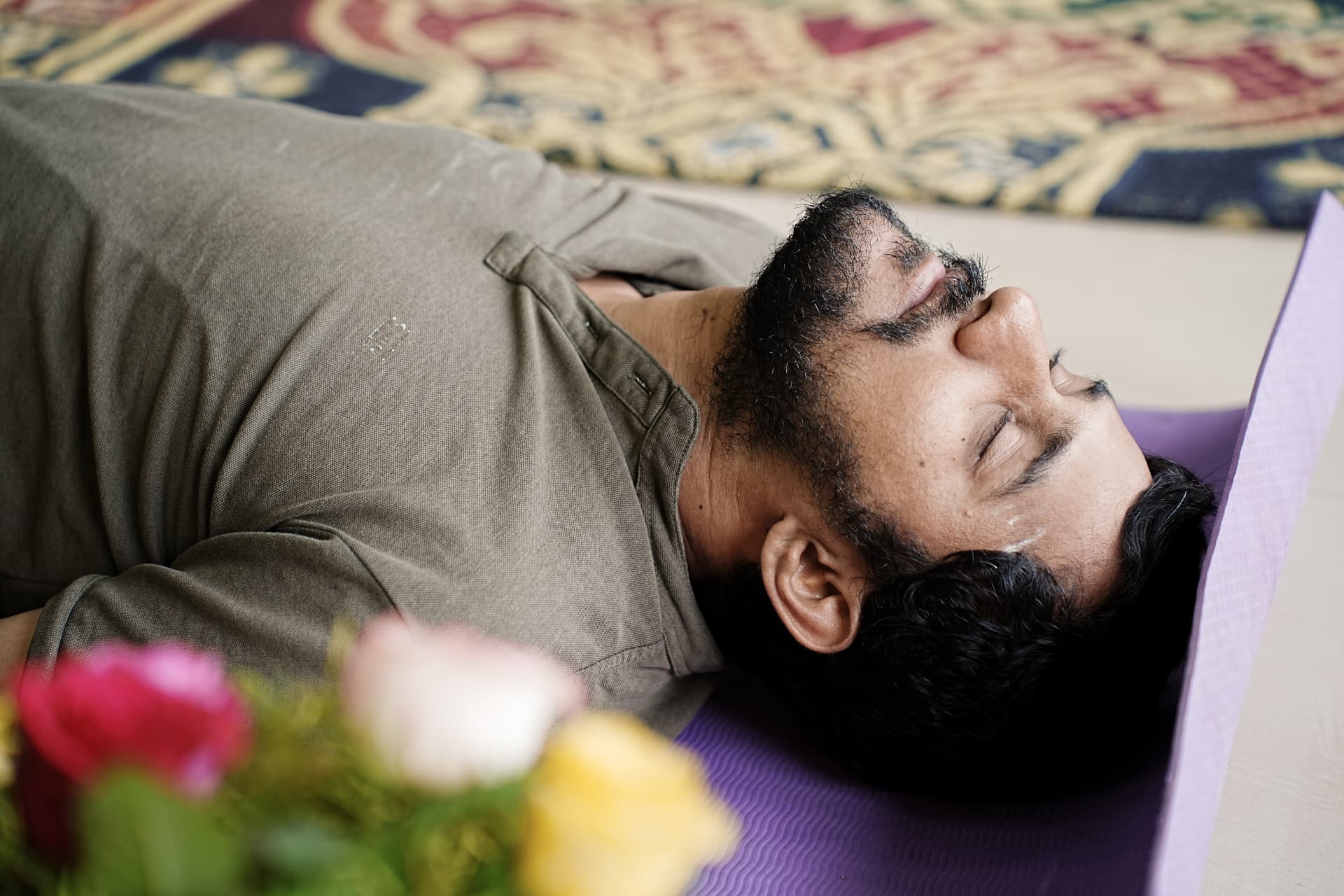A practitioner lying in deep relaxation on a mat